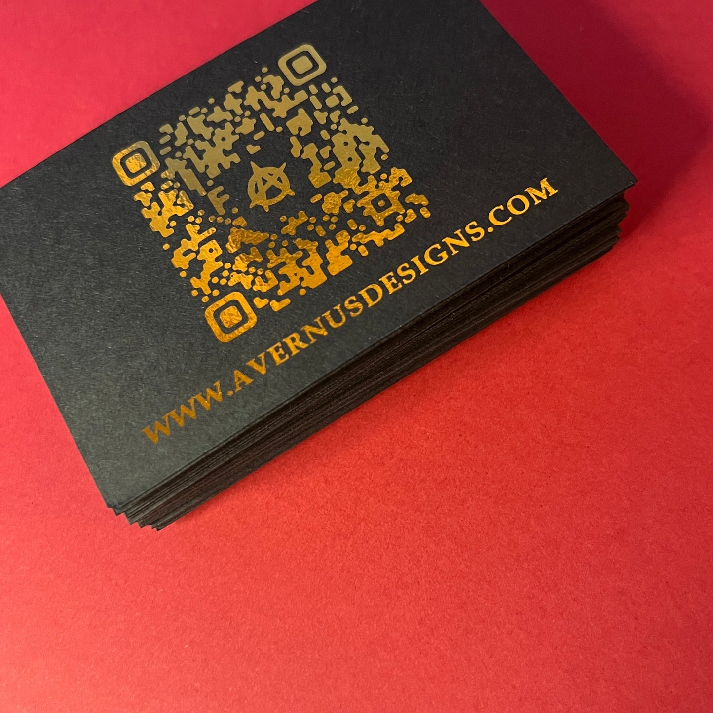 Stack of matte black business cards with a gold foil finish showcasing the use of a QR code. 
